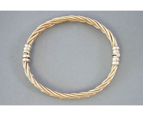 A yellow and white metal heavy twisted bangle. Push in clasp. Diameter: 65.0mm. Hallmarked 9ct gold, London, 1993. 30.6 grams
