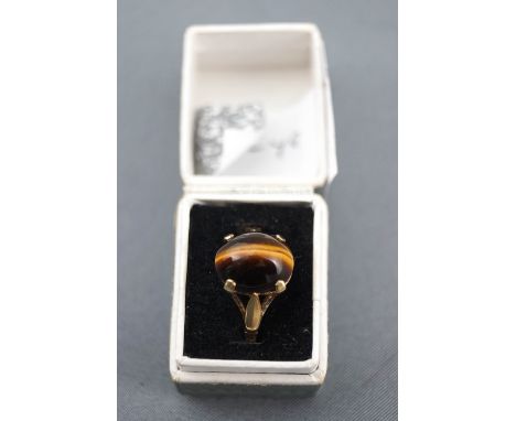 A yellow metal single stone ring.  Set with an oval cabochon cut tigers eye.  Hallmarked 9ct gold, London, 1967. Size R, 3.1 