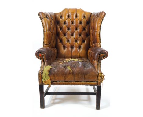 A leather wing back armchair with button back, seat and arms, 118cm high overall