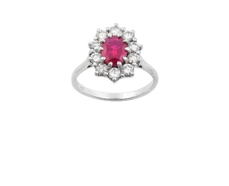 A Ruby and Diamond Cluster Ringthe oval cut ruby within a border of round brilliant cut diamonds, in white claw settings, to 