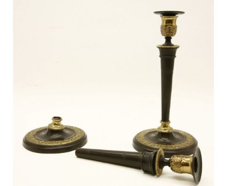 A pair of Regency style bronzed and gilt highlighted candlesticks, with slender tapering supports on a circular spreading bas