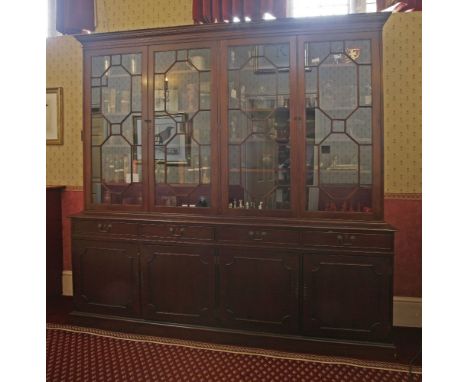 A reproduction mahogany bookcase, in the George lll style, the dentil cornice over four astragal glazed doors, four drawers, 