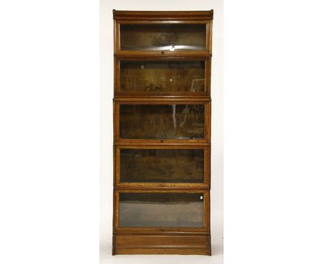 A five tier oak Globe Wernick sectional book case, each section with glazed up and over door, 87cm x 36cm x 214cm