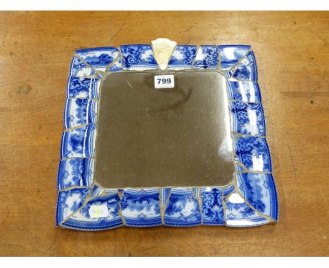 A SQUARE MIRROR IN A MOSAIC CERAMIC FRAME OF BLUE AND WHITE PRINTED PLATE RIM BANDS.   31 x 31cms.