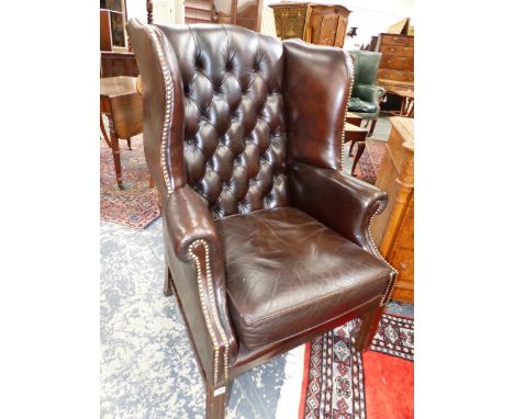 A BUTTON BACKED LEATHER WING ARMCHAIR ON MAHOGANY SHAPED SQUARE SECTIONED LEGS.