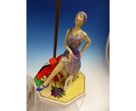 A KEVIN FRANCIS PEGGY DAVIES FIGURAL LAMP BASE, THE LADY WEARING A FLORAL FLAPPER DRESS SEATED ON A CLARICE CLIFF STYLE TEA P