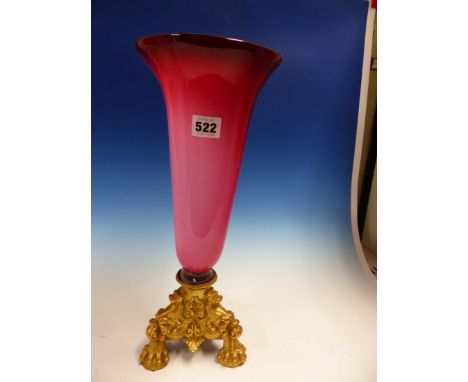 A TONED RUBY OVERLAID GLASS TRUMPET VASE FITTING INTO AN ORMOLU TRIPOD BASE. H 40cms