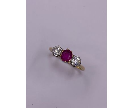 A UNMARKED GOLD RUBY AND DIAMOND THREE STONE CLAW SET RING. FINGER SIZE R, GROSS WEIGHT 2.6grms.