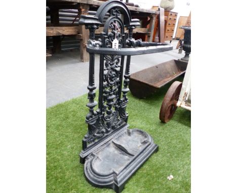 A CAST IRON STICK STAND, THE ROUND ARCH FLORAL BACK PANEL ABOVE REMOVABLE TWO COMPARTMENTAL TRAY.   H 69 x W 40cms.