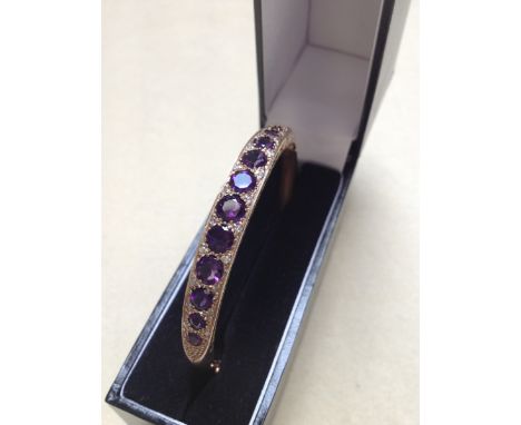 A 9ct GOLD AMETHYST AND DIAMOND CARVED HINGED BANGLE COMPLETE WITH FIGURE OF EIGHT SAFETY CLASP, ENGRAVED TOWARDS THE REVERSE