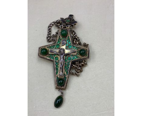 A GREEK ORTHODOX WHITE METAL ARTICUALTED CRUCIFIX INSET WITH GREEN CABOCHON STONES AND BACKED WITH GREEN ENAMEL BEHIND A FILI