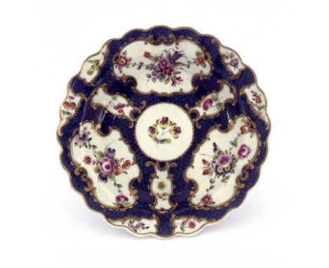 A Worcester scale blue plate, square mark, circa 1770, fluted and lobed rim, painted with European flowers in gilt foliate sc