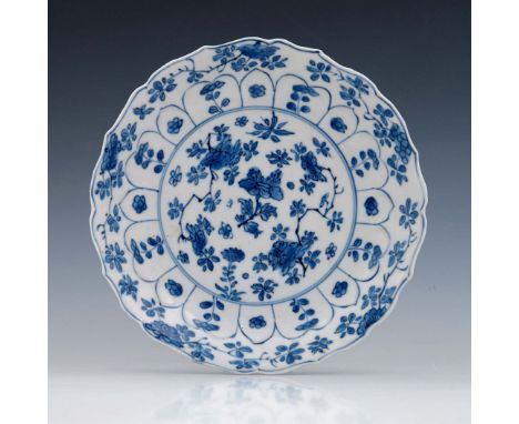 A Chinese blue and white plate, Kangxi mark and probably of the period, ogee rim, painted with alternating lappets of floral 