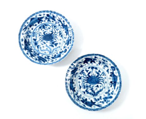 A pair of Chinese blue and white ribbed moulded saucers, kangxi, each painted with a central crab within a rim of fish, doubl