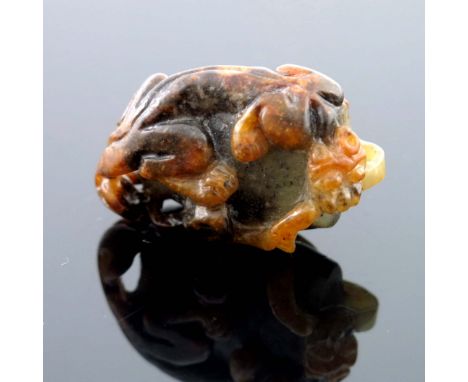 A Chinese jade carving, in the form of a kylin on a rock, russet inclusions, 4.5cm