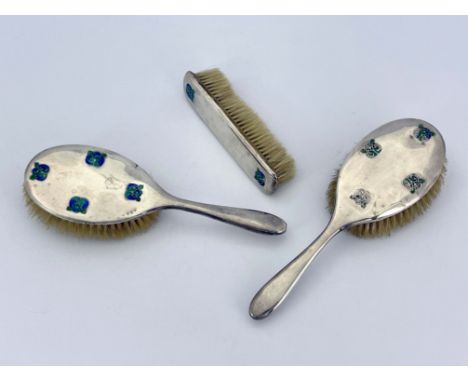 Archibald Knox for Liberty and Co., a set of three Arts and Crafts silver and enamelled brushes, Birmingham 1910, including t