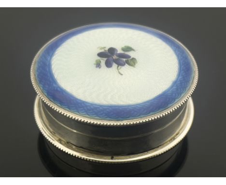 A Continental silver and enamelled box, circular drum form with beaded borders, the lid decorated with a purple flower on cre