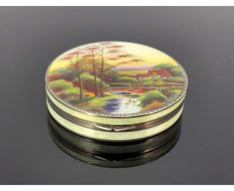 A Continental silver and enamelled compact, import marks London 1928, circular form, the lid painted with a river landscape w