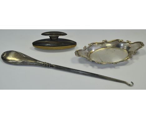 A George V silver shaped oval trinket dish, Birmingham 1916; a large Art Nouveau silver button hook, Birmingham 1912; a nail 