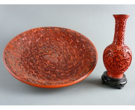 A CARVED CINNABAR STYLE DISH & VASE, the 33 cms diameter dish having central fruit and leaf pattern surrounded by abundant sc