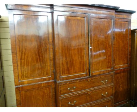 A REGENCY MAHOGANY BREAKFRONT WARDROBE having an inverted curve cornice with reeded moulding over a linen press centre having