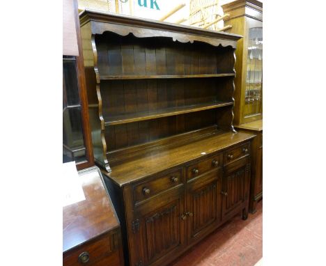 A REPRODUCTION OAK PRIORY STYLE DRESSER, the two shelf rack with decorative canopy and shaped sides over a three drawer, thre