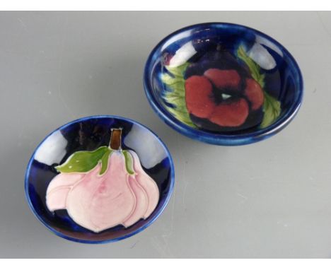 TWO MOORCROFT 'PANSY' & 'MAGNOLIA' SMALL FOOTED BOWLS decorated on cobalt blue grounds to include an 11.5 cms diameter 'Pansy
