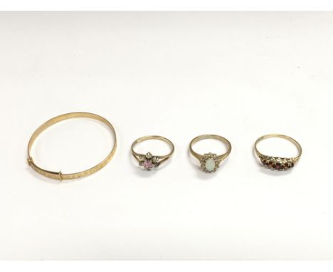 A collection of gold rings set with different stones including opal and an unmarked gold coloured bangle. 6g total. Postage B
