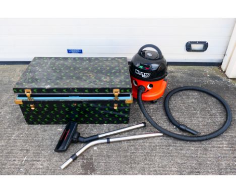 A Henry Hoover vacuum cleaner. Appears used. Vacuum cleaner is presented within a vintage metal chest. (This does not constit