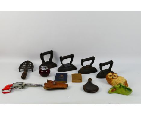 Lot to include 4 x cast irons. Flat iron stand. A Crescent Rustler Ace toy gun. A Ronson ruby red glass table lighter, and si