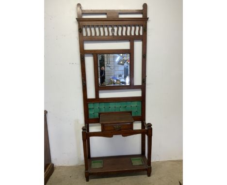 A large early 20th century oak hall stand with bevelled mirror original green tiles and drip trays, with central drawer. W:89