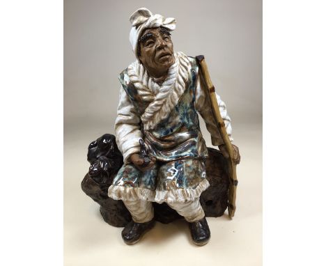 A large pottery figure of an Asian man with pipe. With high firing glazing, with two character marks to interior base. W:36cm