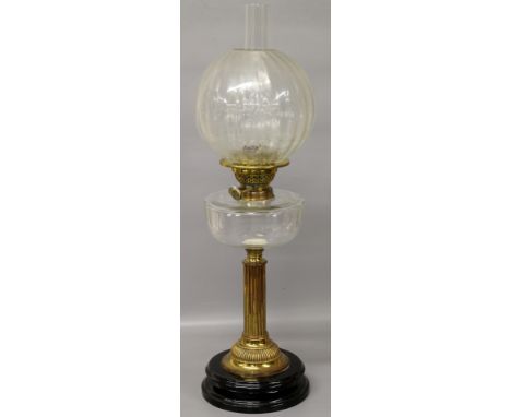 A Victorian oil lamp of column form on black plinth with double burner, clear glass font and glass shade