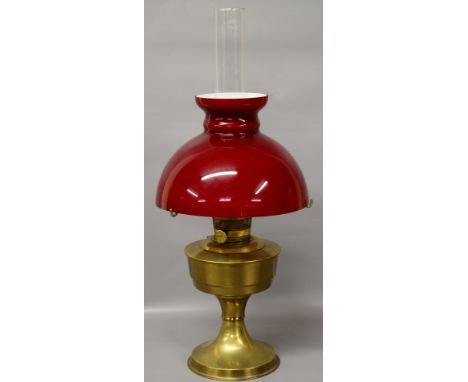 An early 20th Century Aladdin oil lamp with brass reservoir with red shade
