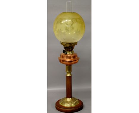 A Victorian double burner oil lamp of column form in wood and brass with brass font and tinted shade