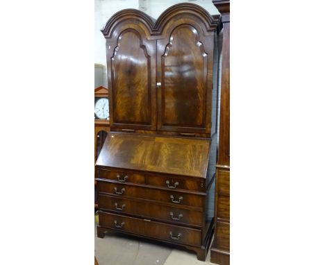 A reproduction mahogany double dome-top bureau cabinet in Georgian style, with the fall-front revealing a shaped drawer and p