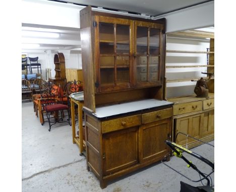 An early 19th century oak 2-section dresser, with glazed cupboard doors, enamel top, and drawers and sliding cupboards under,