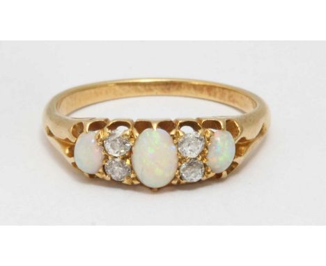 A gold, opal and diamond ring, set with three oval opals, each interspersed by two small diamonds. Gross weight approximately