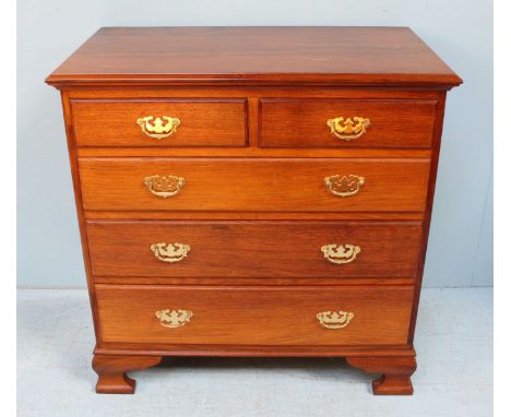A 20th century hardwood chest of two short over three long graduated drawers with brass handles and raised on shaped bracket 