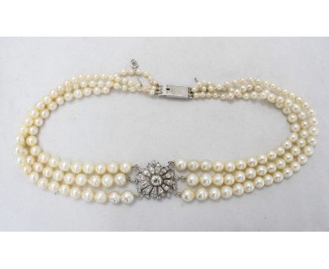 An early 20th Century French diamond centred triple-strand pearl choker necklace, formed of graduated pearls measuring from a