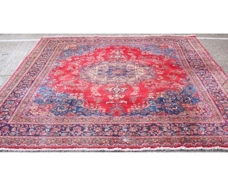 A large hand-knotted Caucasian carpet, with a cream and blue central medallion to a red ground, surrounded by a continuous, m