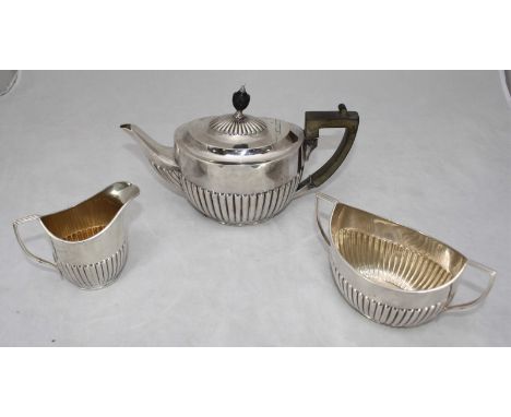 An Edwardian three-piece silver tea set, of oval half-reeded form, comprising teapot, sugar and cream jug, London, 1905-6, by