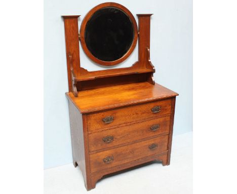 An Edwardian oak dressing table, the central, circular bevelled mirror above a shelf and supported on a base comprising of th