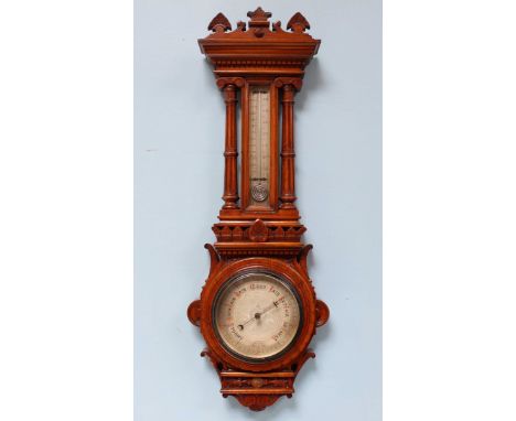 An Edwardian oak cased aneroid barometer, with shaped finial, dentil moulding and a centrally glazed thermometer flanked by c