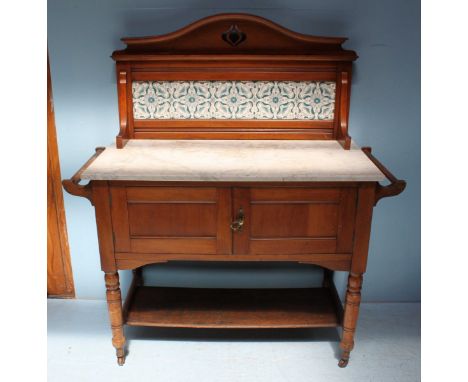 An Edwardian walnut washstand, the tile panelled back above a marble top, over two panelled cupboard doors, raised on turned 