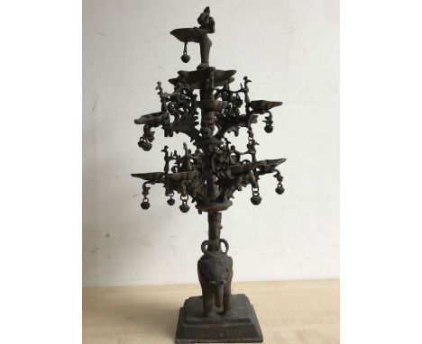 An early 20th century Indian bronze temple lamp, raised upon elephant with rider base and terminating in diety surmount, cast