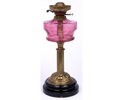 An Edwardian brass oil lamp, with cranberry glass fount and brass burner, on black glazed foot, 45cm h  Polish residues