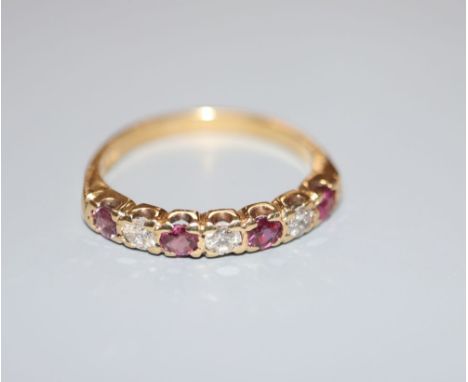 A modern 18ct, three stone diamond and four stone ruby set half hoop ring, size P/Q, gross 3.7 grams.CONDITION: 2 of the rubi