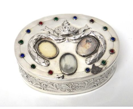 A silver trinket box of oval form, the cover inset with gemstones surrounding three portrait miniatures (two lacking), bearin