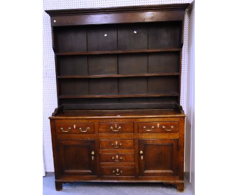 A George III oak dresser, the enclosed three tier plate rack over six short drawers and pair of cupboards on bracket feet, 16